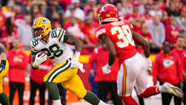 Nov 7, 2021; Kansas City, Missouri, USA; Green Bay Packers running back A.J. Dillon (28) runs the ball as Kansas City Chiefs cornerback L'Jarius Sneed (38) defends during the first quarter at GEHA Field at Arrowhead Stadium. Mandatory Credit: Jay Biggerstaff-USA TODAY Sports